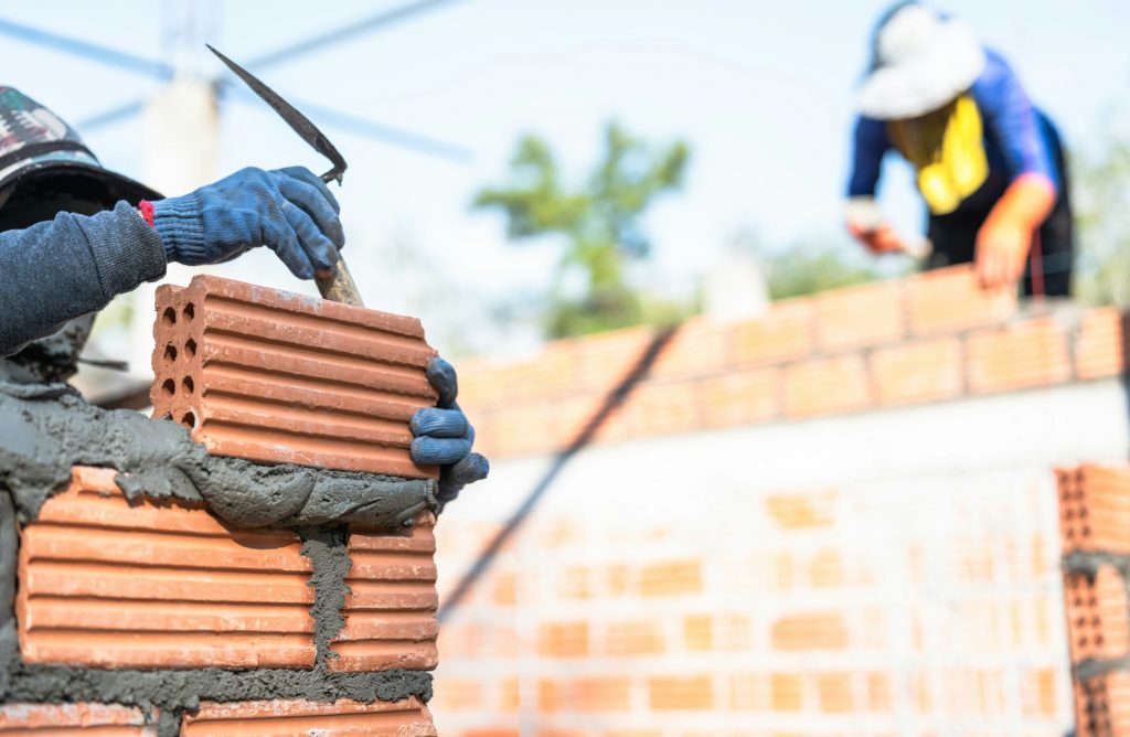 Hand worker masonry installation brick wall on construction site